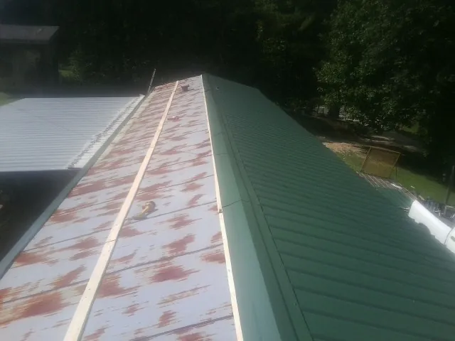Old rusted panels beside newly installed green metal roofing — Wind Damage Roof Repair by Roofing Brothers in Chester